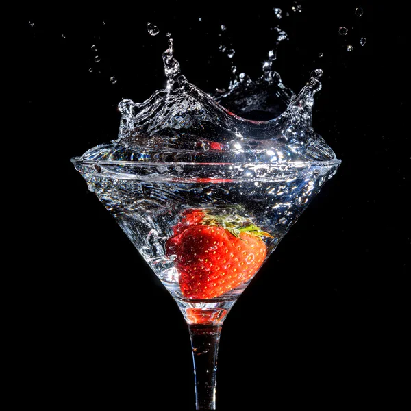 Strawberry splashing into glass of martini