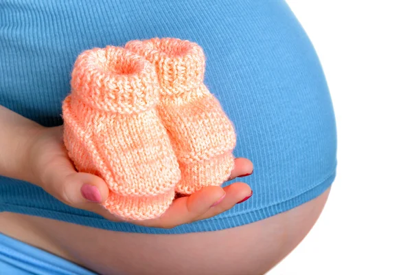 Mujer embarazada sosteniendo un hermoso zapatos de bebé de lana — Foto de Stock