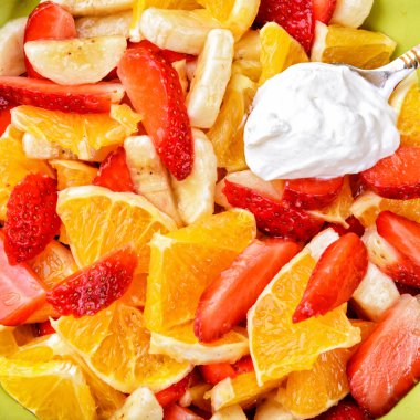 Fruit salad with strawberries, oranges, bananas and sour cream