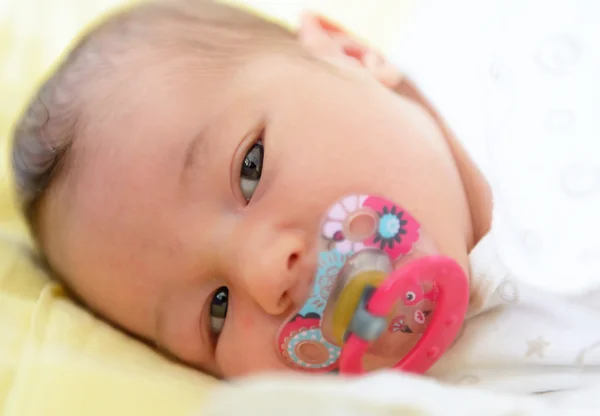 A beautiful newborn girl lies on her bed — Stock Photo, Image