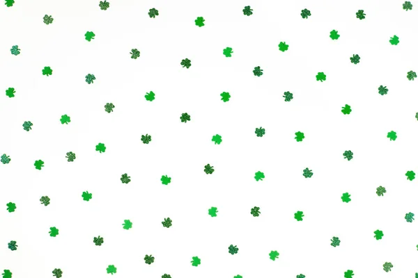 Grün schimmerndes Shamrock-Konfetti spärlich auf weißem Hintergrund — Stockfoto