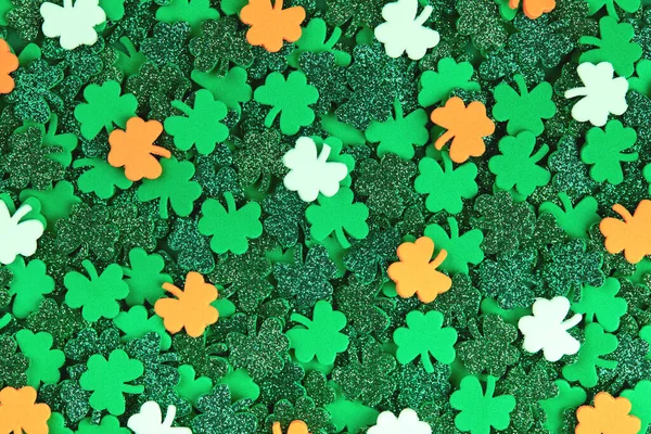 Shamrock confetti texture background with green orange and white lucky clovers