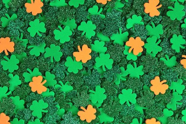 Shamrock confetti tekstury tło z zielonymi i pomarańczowymi szczęśliwymi koniczynami — Zdjęcie stockowe