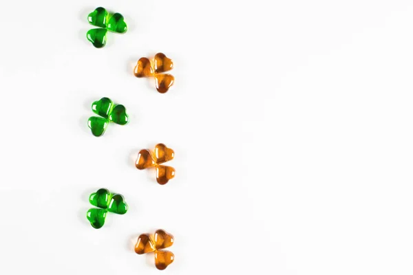Símbolos de trébol hechos de corazones de vidrio verde y naranja sobre fondo blanco —  Fotos de Stock