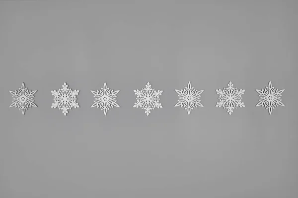 Ряд белых деревянных снежинок на сплошном сером фоне — стоковое фото