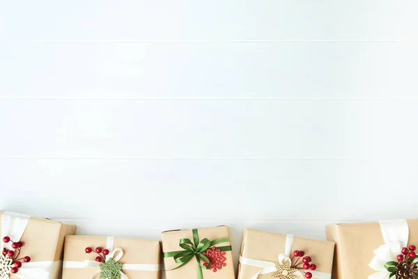 Rand van geschenkdozen verpakt in kraftpapier op witte houten bureauondergrond — Stockfoto