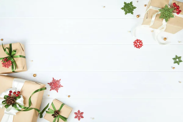 Drie geschenkdozen verpakt in kraftpapier op witte houten bureauondergrond — Stockfoto