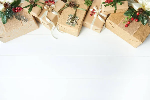 Border of gift boxes wrapped in kraft paper on white wood desk background