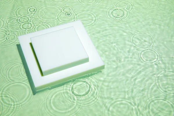 Üres fehér négyzet dobogó átlátszó zöld tiszta víz háttér — Stock Fotó