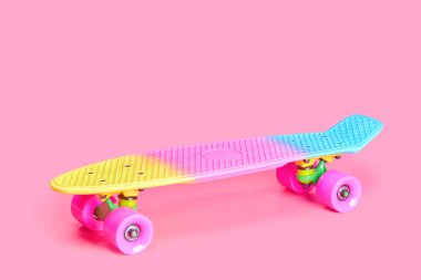 Pembe arka planda izole edilmiş gökkuşağı plastiği Penny kaykayı