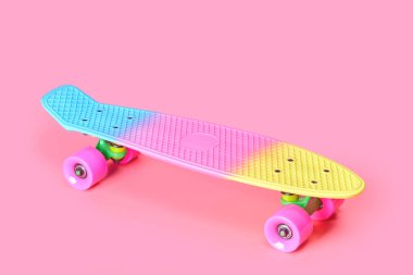 Pembe arka planda izole edilmiş gökkuşağı plastiği Penny kaykayı