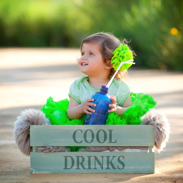 Cute girl child sitting in box with bottle of water — Stock Photo, Image