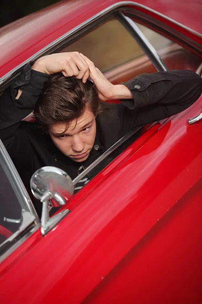 Joven rockero peinando pelo en los años cincuenta coche — Foto de Stock