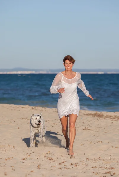 ペットの犬とビーチを走る女性 — ストック写真