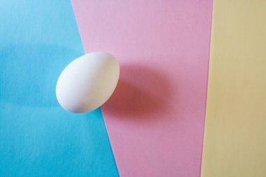 Paskalya konsepti. Pastel renklerde çok renkli bir arka planda beyaz yumurta. Tavuk yumurtladı. Doğal organik ürünler. Metin için kopyalama alanı olan Mutlu Paskalyalar kartı.