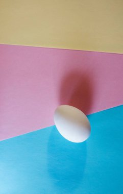 Paskalya konsepti. Pastel renklerde çok renkli bir arka planda beyaz yumurta. Tavuk yumurtladı. Doğal organik ürünler. Metin için kopyalama alanı olan Mutlu Paskalyalar kartı.