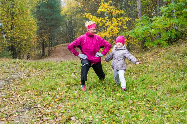 Kobieta z dziewczyna robi aerobik w parku jesień — Zdjęcie stockowe