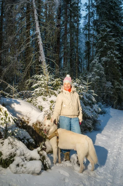 Vrouw met hond in winter bos op een wandeling — Stockfoto