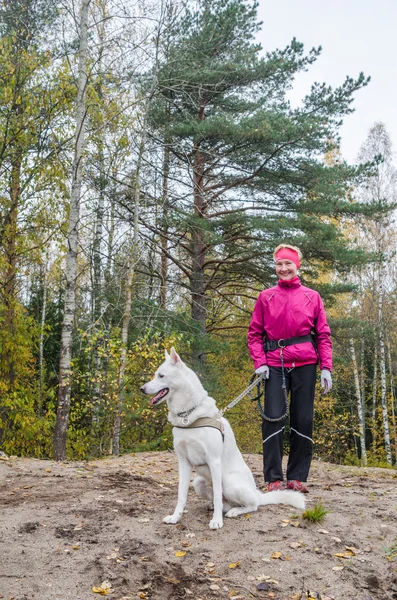 Femme avec un chien blanc dans un bois — Photo