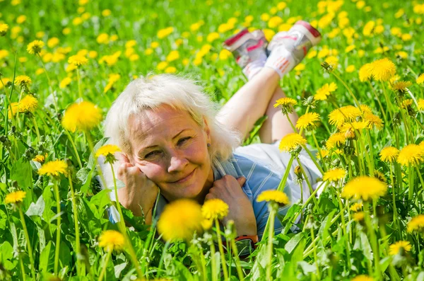 A woman lies in a clearing and sniffs a flower — Stock Photo, Image