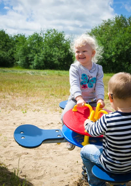 Boy and girl swinging on a swing — Stock Photo, Image