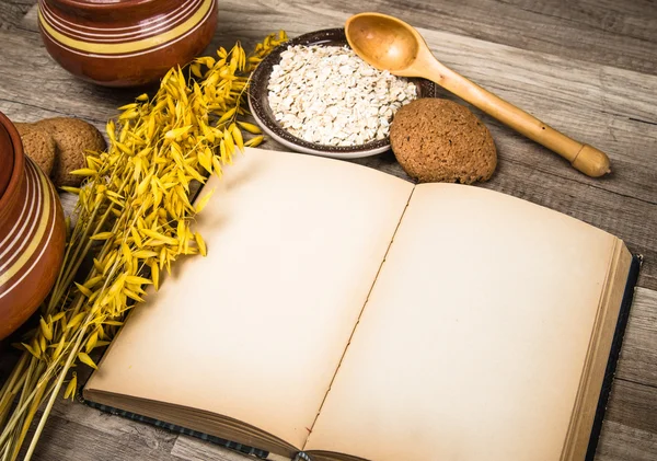 Haferflockenplätzchen und ein altes Rezeptbuch auf dem Küchentisch — Stockfoto