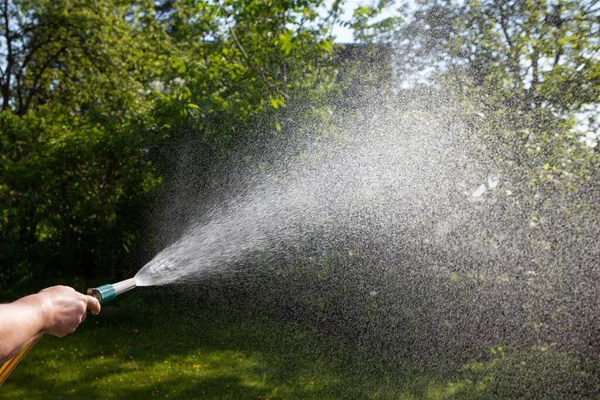 女がホースで庭に水をやる。空気中の水滴. — ストック写真