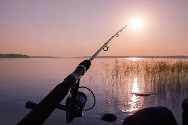 Canne à pêche dans le contexte d'un coucher de soleil rose calme désert Photo De Stock