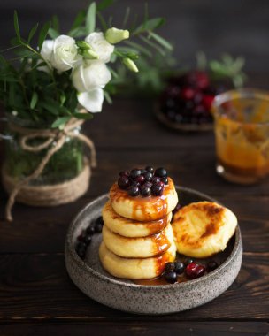 Siyah üzümlü yaz kahvaltısı. Karamelli ve böğürtlenli peynirli kekler güzel bir kahvaltı servisidir. Vazoda beyaz çiçeklerle yemek servisi.