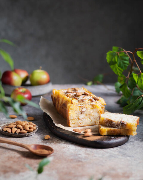 A piece of apple cake with nuts on a plate. Apple dessert on a brown background. Apple pie with hazelnuts and cinnamon. Autumn spicy pastries