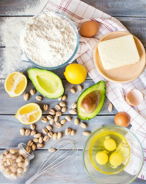 Organic products from the farmer's market. Avocado, pistachios, flour, eggs, butter and lemon on a wooden table. Products for making avocado cupcake