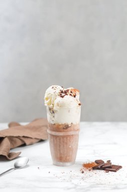 Vanilyalı ve çikolatalı dondurma. Çikolata parçacıklı. Hafif bir arka planda kaşıkla tatlı.