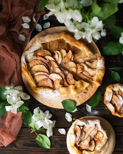 Baked sweet apple pie with honey and cinnamon on a wooden table. Spring biscuits and a blooming apple tree