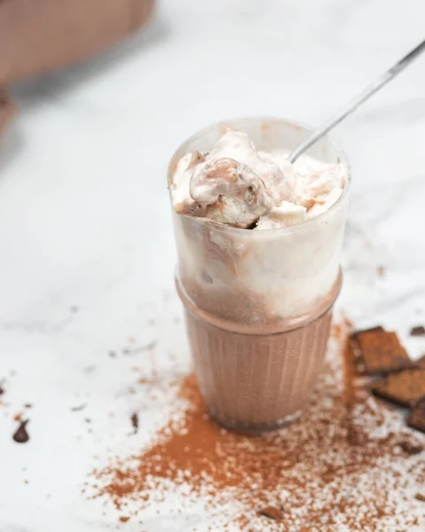 Vanilla and chocolate melted ice cream. Chocolate chip. Dessert on a light background with a spoon.