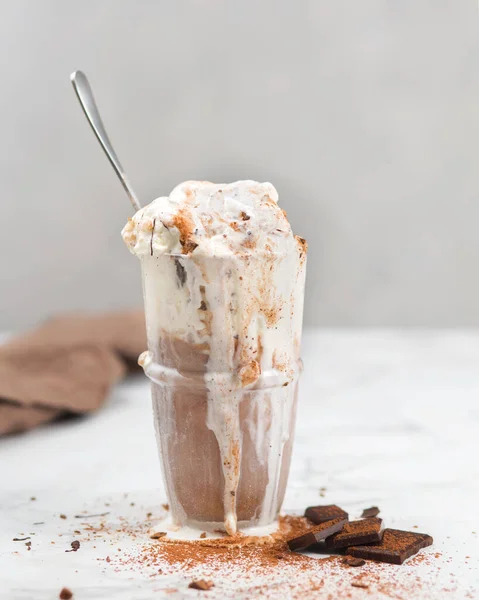 Vanilla and chocolate melted ice cream. Chocolate chip. Dessert on a light background with a spoon.