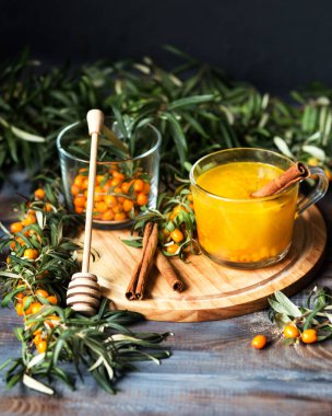 Tahta bir masada sıcak bir içki. Tarçınlı ve ballı karabuğday çayı. Tarçın çubukları ve taze deniz dikenli dallar. Böğürtlenden yapılmış sonbahar çayı