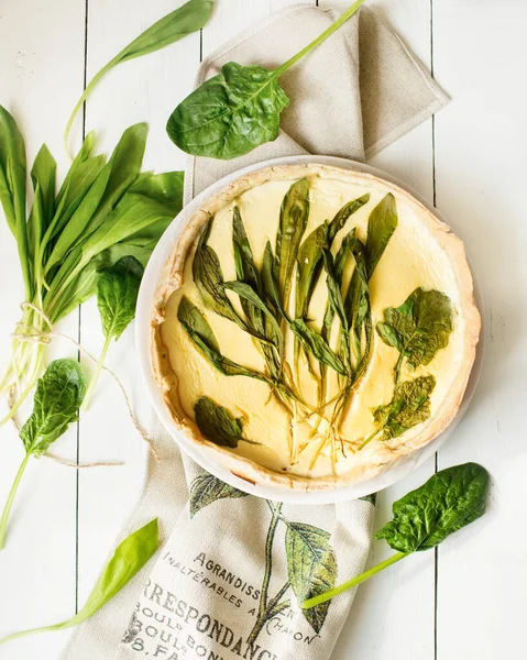 French cuisine. Quiche with spinach and wild leeks. Green food. French pastries on a white table. wild garlic.