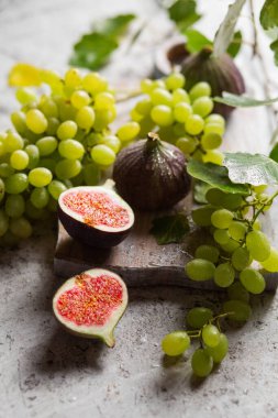 Sonbahar hala hayattır. Tahtadaki incir ve üzümler. Hasat ve yeşil yapraklar. Sonbahar arkaplanı. Arka planda sonbahar meyveleri. Bir demet üzüm ve incir.