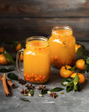 Ahşap arka planda sonbahar içkisi. Mandalinalı deniz dikenli çay. Isınan çilek suyu. Tarçın ve anasonlu sıcak çilek çayı..