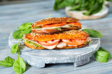 Lezzetli bir yemek. Domatesli sandviç, ıspanak ve tavuk. Ahşap bir arka planda Aperatif. Susamlı çörek. Amerikan mutfağı. Taze yemek..