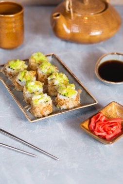 Japon mutfağı. Gri bir arkaplanda yuvarlanıyor. Asya usulü yemek servisi. Japon yemeği ve çayı içmek. Suşi, zencefil ve soya sosu. Yemek fotoğraflarında metin için yer.