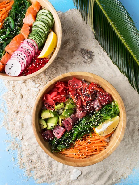 Hawaiian cuisine. Tropical food with fish, vegetables. Lunch on the beach. An exotic dish. Poke with tuna and salmon. A bowl with healthy food. Avocado and seafood.