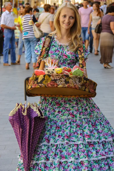 Chica vendedor con caramelo vestido con ropa retro en la ciudad histórica —  Fotos de Stock