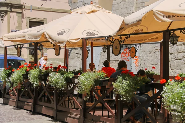 Pessoas que descansam no café ao ar livre no centro histórico da cidade. Lviv, Reino Unido — Fotografia de Stock