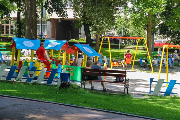 Ludzie z dziećmi na plac zabaw w parku Ivan Franko. Lwów, Wielka Brytania — Zdjęcie stockowe