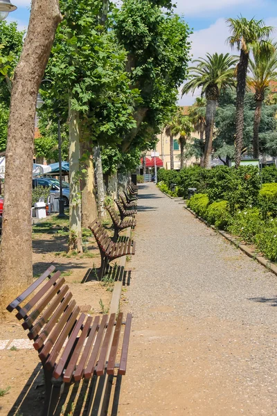 Vicolo vuoto con panchine nel parco cittadino. Vada, Italia — Foto Stock