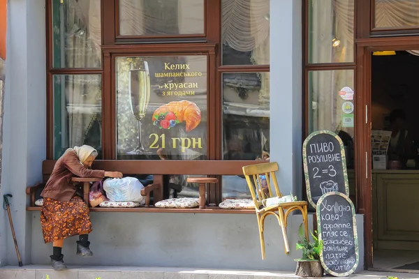 Stara kobieta siedzi w pobliżu wejścia do restauracji w Lwowie, Ukraina — Zdjęcie stockowe