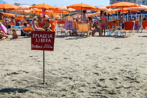 Um ponteiro para a praia livre perto de pessoas descansando em Viareggio, É — Fotografia de Stock