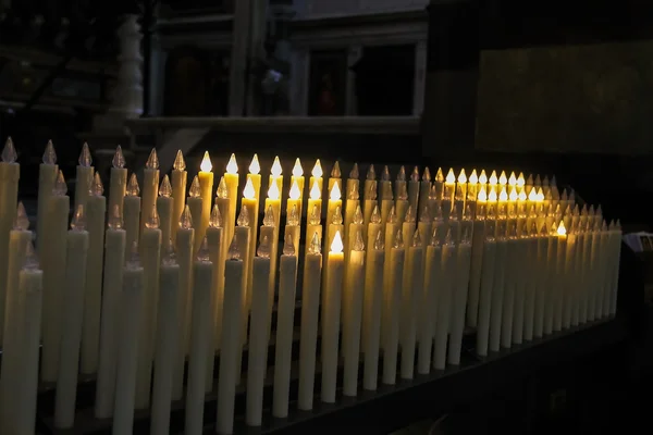 Moderne elektrische kaarsen in de kerk op donkere achtergrond — Stockfoto