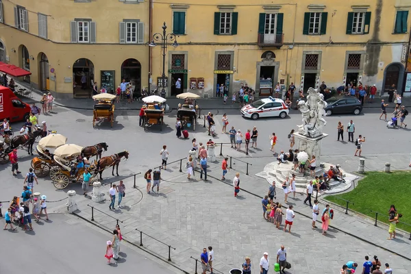 Toeristen in de buurt van de fontein met engelen op Piazza del Duomo in Pi — Stockfoto